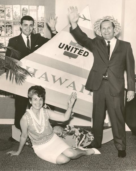 Vintage black-and-white photo of travelers posing with a United Airlines Hawaii sign