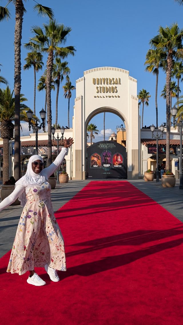 A visitor on the red carpet at the Universal Studios Hollywood entrance arch