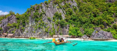 A traditional outrigger boat in a turquoise lagoon in Palawan