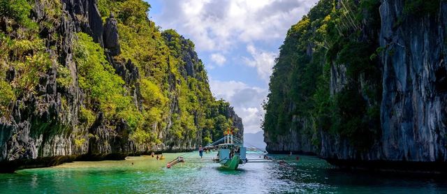 A boat in the Big Lagoon among limestone cliffs in El Nido, Palawan